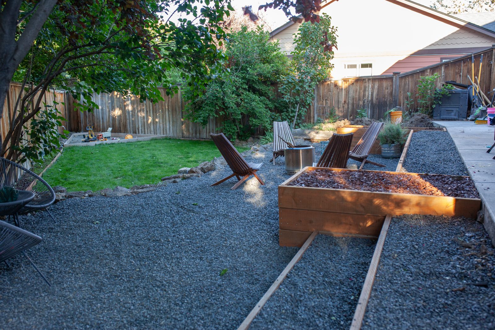 Backyard after landscaping with gravel patio, raised beds, and seating area